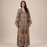 Beige abaya featuring artistic botanical motifs in warm terracotta and soft blue tones, arranged in a beautiful symmetrical pattern