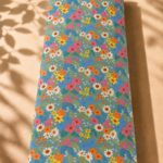 Cheerful floral print featuring colorful mini flowers in pink, orange, yellow, and white on a fresh blue background.