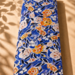 Vibrant floral print featuring orange and soft ivory flowers with deep navy leaves on a rich royal blue background.