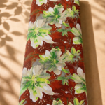 Bold floral print featuring large ivory and fresh green blossoms on a rich rust-red background.