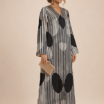 Striking black and white abaya featuring fine vertical stripes with bold oversized polka dots for a modern geometric look