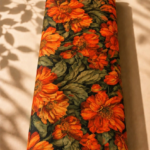 Deep black chiffon adorned with vivid orange florals and rich olive-green foliage for a bold elegant look - Italian Chiffon (CF01)