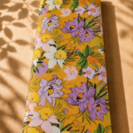 Mustard orange cotton with vibrant purple, white, and yellow tropical florals, accented with lush green leaves - Italian Cotton (PC02)