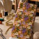 Vibrant floral print in purple, blush and ivory tones over a warm mustard background.