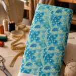 Vibrant blue floral and leafy motifs in layered aqua and turquoise tones, accented with subtle lime details on a soft mint background.