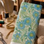 Elegant sky-blue florals surrounded by flowing mint and sage-green foliage on a soft ivory background.