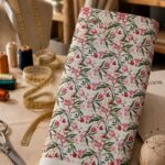 Delicate pink and red blossoms with flowing green leaves, accented by tiny golden stars on a soft white background.