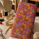 Vibrant yellow and lavender wildflowers with delicate green foliage, densely scattered across a bold coral-red background.