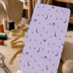 Minimal celestial print with black crescent moons, delicate stars, and tiny dots on a soft lavender background.