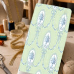 Elegant vintage print with blue floral medallions, delicate bows, and ornamental garlands on a soft mint green background.