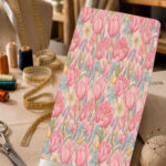 Soft pink tulip floral print with delicate blue, lavender, and yellow accents on a pale blush background.