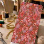 Romantic pink and lilac floral print with muted green leaves on a rich coral-red background.