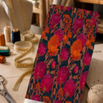 Rich magenta and vivid orange floral print on a deep teal background with warm brown foliage.