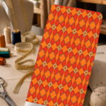 Vibrant orange geometric print with repeating red diamond and petal motifs.