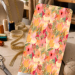 Soft watercolor floral print in coral, peach, pink, and yellow tones with muted green leaves.