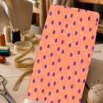 Bold purple polka dots on a soft coral-peach textured background.