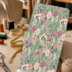 Delicate pink, blue, and ivory wildflowers with soft green leaves on a sage green background.