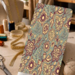 Vintage floral and butterfly motifs in cream and deep plum on a soft sage green background.