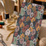 Vintage floral print in muted orange, blush, sage green, and cream on a deep blue-grey background.